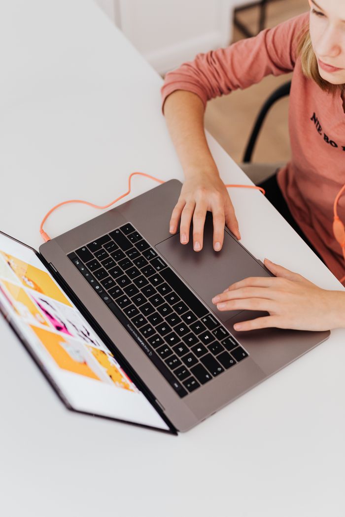 Young woman using a laptop at a desk, showcasing a productive workspace.