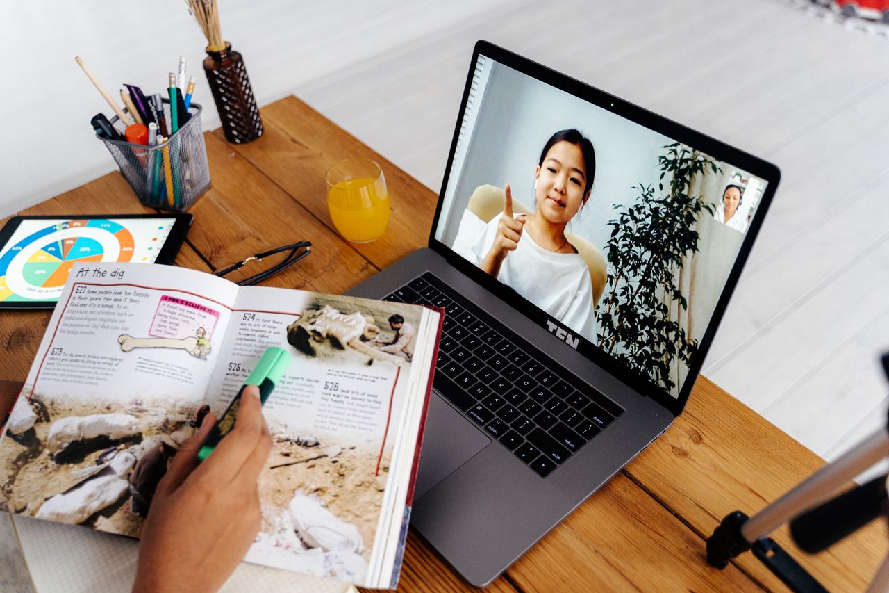 Online teaching session with digital tools, featuring a woman on a laptop screen and educational materials.